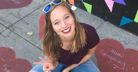 Au pair sentada en la acera sonriendo a la cámara