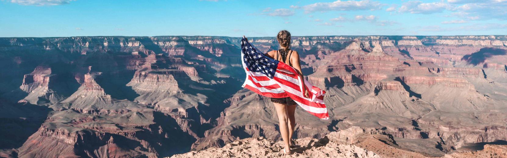 Au pair sosteniendo una bandera estadounidense en el Gran Cañón