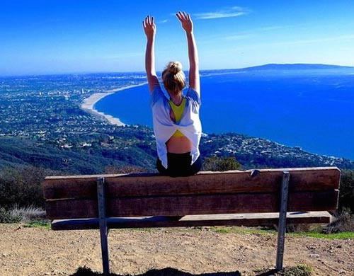 Au pair sentada en un banco con vistas al mar