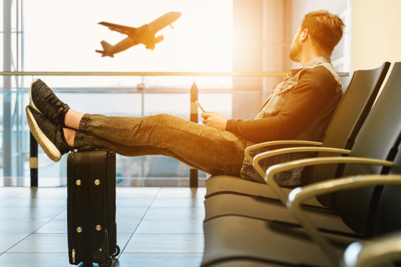Au pair sentado en el aeropuerto mirando cómo despega un avión